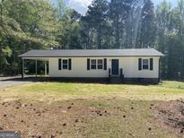 Charming single-story home features white siding, black shutters, and a covered carport for convenient parking at 300 Wood Rd., Hampton, GA 30228