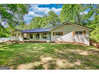 Beautiful single-story home with a black metal roof, white painted brick and charming front porch at 1200 Ridgeway Rd, Covington, GA 30014