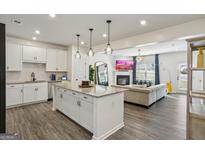 Open-concept living room showcases a modern kitchen with island and a cozy fireplace at 375 Crider Ct, Woodstock, GA 30188