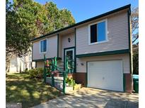 Charming two-story home featuring vinyl siding, green trim, a garage, and landscaped front yard at 2406 Redfield Dr, Norcross, GA 30071