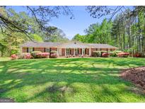 Charming brick ranch home featuring a lush, green lawn and mature landscaping at 242 Hickory Rd, Fayetteville, GA 30214
