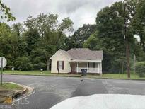 Charming single-story home with a welcoming front porch and well-maintained lawn on a cloudy day at 116 Stewart Ave, Jonesboro, GA 30236