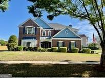 Charming two-story brick home with a manicured lawn and patriotic flag display at 1600 Prospect Pl, Locust Grove, GA 30248