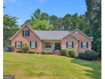 Charming brick home featuring a well-manicured lawn and mature trees on a sunny day at 75 The Farm Rd, Mcdonough, GA 30252