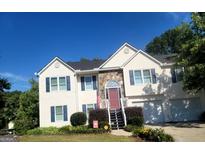 Charming two-story home featuring stone accents, a well-manicured lawn, and a welcoming red front door at 3870 Michaels Creek Ct, Loganville, GA 30052