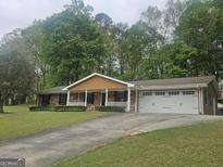 Charming brick home with a welcoming front porch, well-manicured lawn, and an attached two-car garage at 103 Belair Ln, Stockbridge, GA 30281