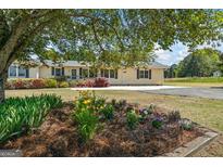 Charming single-story home with manicured front yard and mature landscaping, including a beautiful flower bed at 424 N Green Cir, Mcdonough, GA 30252