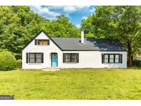 Charming brick home featuring a welcoming blue front door and lush green lawn at 6127 Floyd Ne St, Covington, GA 30014