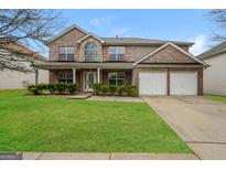 Charming two-story brick home with a well-manicured lawn, covered porch, and attached two-car garage at 3675 Arminto Dr, Ellenwood, GA 30294
