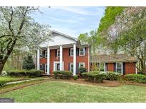 Traditional red brick home boasts a symmetrical facade with white columns and well-manicured landscaping at 173 Darwish Dr, Mcdonough, GA 30252