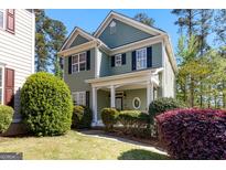 Charming two-story home with a green exterior, black shutters, and landscaped front yard at 217 Christina Ct, Peachtree City, GA 30269