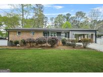 Charming brick home featuring a well-manicured lawn and an inviting covered carport at 3387 Oak Dr, Lawrenceville, GA 30044