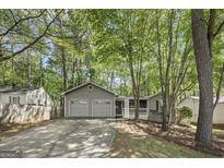Charming single-story home featuring a spacious two-car garage and inviting front porch surrounded by lush greenery at 385 Lakeshore Dr, Stockbridge, GA 30281