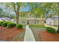 Charming two-story home with a well-manicured lawn, beautiful landscaping, and a welcoming walkway at 4437 Ben Hill Rd, Atlanta, GA 30349