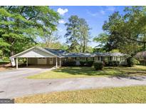 Traditional single story home featuring an attached carport and well maintained lawn and mature trees at 30 Circle Dr, Hampton, GA 30228
