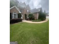 Charming brick home with well-manicured landscaping, flower beds and a walkway leading to the front door at 45 Anna Dr, Covington, GA 30014