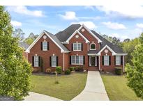 Impressive red brick home featuring manicured lawn, black shutters, and elegant architectural detailing at 2351 Rabbit Farm Cir, Loganville, GA 30052