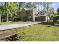 Inviting two-story brick home featuring a lush, green front yard and a convenient two-car garage at 180 Paces Dr, Fayetteville, GA 30215