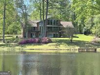 Beautiful exterior view of the brick home overlooking a scenic lake and lush greenery at 4383 Pool Rd, Winston, GA 30187