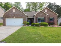 Charming brick home features a two-car garage and manicured front lawn with mature landscaping at 327 Viceroy Curv, Stockbridge, GA 30281