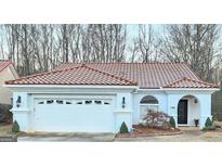 Charming single-story home featuring a red tile roof, arched window, and a two-car garage at 144 Garden Walk, Stockbridge, GA 30281