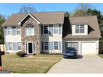 Inviting two-story home with a stone facade, blue shutters, well-manicured lawn, and attached garage at 1055 Field View Dr, Mcdonough, GA 30253