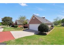 Charming brick home featuring an attached two-car garage and well-maintained landscaping under a clear blue sky at 1313 Jubilee Ln, Mcdonough, GA 30253