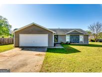Charming single-story home featuring a two-car garage, stone accents, and a well-maintained lawn at 2582 Rosecommons Dr, Hampton, GA 30228