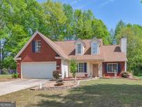 Charming two-story home with brick and vinyl siding, attached garage, manicured lawn, and mature trees at 2040 Elm Grove Ln, Hampton, GA 30228