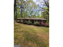 Charming single-story brick home with mature trees and colorful landscaping at 5730 Koweta Rd, South Fulton, GA 30349