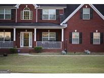 Traditional two story brick home with a cozy front porch and well manicured lawn at 419 Tea Rose N Ln, Stockbridge, GA 30281