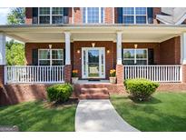 Charming red brick home featuring a welcoming front porch with white columns and manicured landscaping at 419 Tea Rose N Ln, Stockbridge, GA 30281