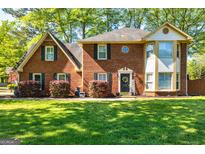 Charming brick home with lush green lawn and mature landscaping, offering great curb appeal at 310 Hamdon Kells, Peachtree City, GA 30269
