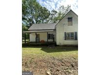Exterior of a rundown two-story home with peeling paint and a covered porch, surrounded by mature trees and green grass at 6183 Collins Ne St, Covington, GA 30014