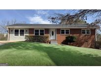 Charming red brick home with well-manicured lawn, complemented by mature shrubbery and a classic front door at 1745 Rockbridge Nw Rd, Conyers, GA 30012