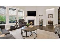 Comfortable living room featuring a fireplace, neutral tones, and a large window providing natural light at 5910 Stellata Cir, Cumming, GA 30028