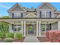 Charming front porch with stone accents, white columns, and decorative landscaping at 185 Discovery Lake Dr, Fayetteville, GA 30215