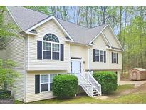 Inviting home featuring light siding, black shutter accents, neat landscaping, and a cozy shed in its backyard at 28 Willow Ridge Dr, Hampton, GA 30228