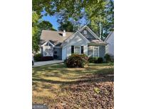 Charming one-story home with grey siding, complemented by well-maintained landscaping and flowering bushes at 411 Sherrels Frd, Peachtree City, GA 30269