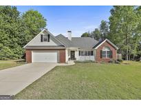 Charming single-story home with a brick facade, manicured lawn, and two-car garage at 140 Pecan Ridge Dr, Fayetteville, GA 30215
