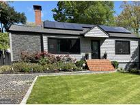 Charming home featuring a well-manicured lawn, brick steps, stone accents, and solar panels at 727 Channing Dr, Atlanta, GA 30318