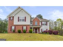 Two-story home featuring a mix of brick and siding, complemented by red shutters and manicured landscaping at 3156 Oak Ridge Ln, Loganville, GA 30052