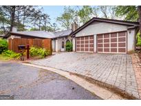Charming home featuring a two-car garage and a well-maintained interlocking brick driveway, set amidst lush greenery at 5082 Highland Hills Ct # 93, Stone Mountain, GA 30088
