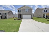 Two story home with a gray exterior, white garage door, and landscaped yard at 157 Oliver Dr, Locust Grove, GA 30248