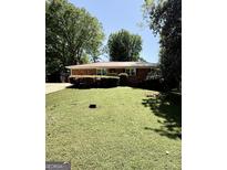 Charming brick ranch home with a well-manicured lawn, mature trees, and a metal roof at 1093 Grace Sw St, Mableton, GA 30126