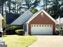 Charming one-story home featuring a well-manicured lawn and a two-car garage with a brick facade at 110 S Fairfield Dr, Peachtree City, GA 30269