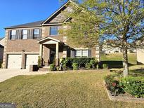 Beautiful two-story brick home with a two car garage and a well-manicured lawn in a suburban neighborhood at 1166 Vienna Ct, Hampton, GA 30228