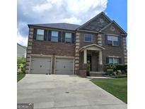 Charming brick home boasts a two-car garage, covered porch, and well-maintained landscaping at 1166 Vienna Ct, Hampton, GA 30228