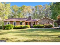 Charming single-story home featuring stone accents, well-manicured lawn, and mature trees at 215 North Mourning Dove N Dr, Fayetteville, GA 30215