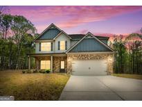 Charming two-story home with a brick facade, gray siding, and a two-car garage under a beautiful violet sky at 1011 Austin Rd, Ellenwood, GA 30294
